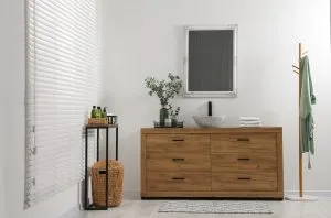 Modern bathroom interior with stylish mirror, eucalyptus branches, vessel sink and wooden vanity